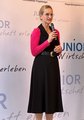 Eine Frau steht vor einer JUNIOR-Werbewand und spricht in ein Mikrofon.