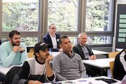 Erwachsene Schüler sitzen an Tischen im Unterricht. 