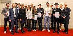 Bernhard-Strigel-Gymnasium Memmingen Eine Schulklasse steht auf einem roten Teppich und hält ihre Urkunden in die Kamera.