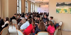 Schüler*innen in Kleingruppen sitzen zusammen und reden miteinander.