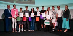 Eine Gruppe von Schülern posiert, umringt von vier Erwachsenen, mit Urkunden in der Hand für ein Foto.