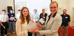 Sandra Stenger Eine Frau mit Brille und blondem Haar überreicht einer Jugendlichen eine Urkunde und einen Preis.