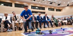 Ein Junge führt dem Publikum auf einer markierten Fläche am Boden den selbstentwickelten Roboter vor. 