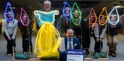 Eine Gruppe von Schülern sowie drei Erwachsenen präsentieren ein Foto-Projekt. Lichtschlangen zeichnen die Silhouetten von Wichtelmützen und einem Kleid nach.