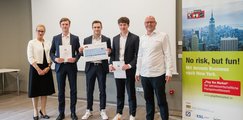 Drei Schüler stehen in der Mitte von einer erwachsenen Frau und einem Mann. Die drei Jungs halten jeweils eine Urkunde in der Hand. 