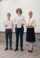 Zwei Jungs halten jeweils eine Urkunde in die Kamera. Rechts neben ihnen steht eine Frau und lacht ebenfalls in die Kamera.