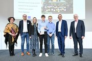 Eine Gruppe aus Männern, Schüler*innen und einer Frau posieren für ein Foto. 