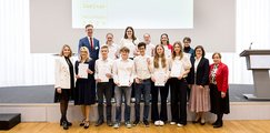 Goethe-Gymnasium Regensburg Auf dem Bild sieht man eine Gruppe Jugendlicher, die lächelnd ihre Urkunden in die Kamera halten. Sie stehen dabei auf einer Bühne.