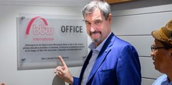 Dr. Markus Söder, Bayerischer Ministerpräsident, zeigt auf das Schild des neuen bbw-Projektbüros in Kapstadt. Er ist umringt von applaudierenden Menschen.