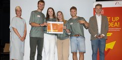 Eine Frau und ein Mann umrahmen eine Gruppe von Student*innen, die eine Urkunde in der Hand halten.