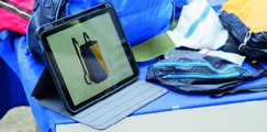 Auf einem Tisch stehen Taschen aus recyceltem Gleitschirmstoff sowie ein Tablett mit einer Animation.