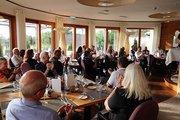 Eine Gruppe von Menschen, die an Tischen sitzen, klatscht Beifall.