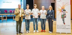 Das Tema der Johann-Pachelbel-Realschule Nürnberg Drei Jugendliche mit einer Auszeichnung in der Hand posieren mit einem Mann und einer Frau für ein Foto.