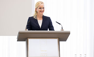 Sandra Stenger, bbw-Vorstandvorsitzende Eine blonde Frau mittleren Alters steht an einem Pult und hält eine Rede. Sie lächelt.