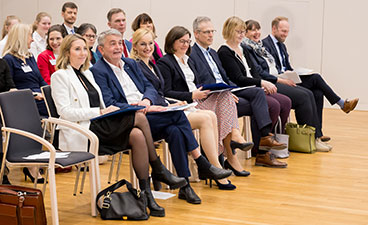 Stolz, Brossart und Stenger gratulierten den Siegerschulen In der ersten Reihe des Publikums sitzen acht Männer und Frauen und blicken lächelnd in Richtung Bühne.