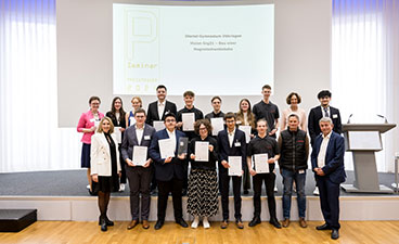 Illertal-Gymnasium Vöhringen Auf der Bühne steht eine Schulklasse, welche in die Kamera lächelt. Die Jugendlichen halten Urkunden und einen Preis in der Hand.
