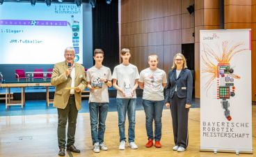 Schüler der Johann-Pachelbel-Realschule Nürnberg Drei Jugendliche mit einer Auszeichnung in der Hand posieren mit einem Mann und einer Frau für ein Foto.