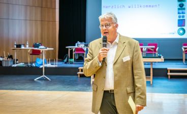 Michael Mötter, stellvertretender Geschäftsführer des bbw e. V. Ein Mann hält ein Mikrofon in der Hand und spricht zu Publikum.