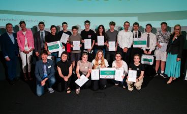 Eine Gruppe von Schülern posiert mit Urkunden in der Hand gemeinsam mit mehreren Erwachsenen für ein Foto.
