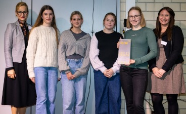 Frauen und Schülerinnen posieren für ein Foto. Eine Person hält eine Auszeichnung in der Hand. Frauen und Schülerinnen posieren für ein Foto. Eine Person hält eine Auszeichnung in der Hand.