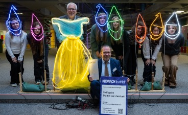 Eine Gruppe von Schülern sowie drei Erwachsenen präsentieren ein Foto-Projekt. Lichtschlangen zeichnen die Silhouetten von Wichtelmützen und einem Kleid nach. Eine Gruppe von Schülern sowie drei Erwachsenen präsentieren ein Foto-Projekt. Lichtschlangen zeichnen die Silhouetten von Wichtelmützen und einem Kleid nach.