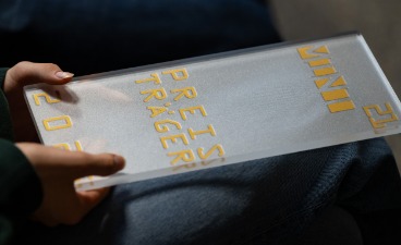 Nahaufnahme des Preises: Eine Glasscheibe auf der Mint21, Preisträger sowie die Jahreszahl 2025 steht. Nahaufnahme des Preises: Eine Glasscheibe auf der Mint21, Preisträger sowie die Jahreszahl 2025 steht.