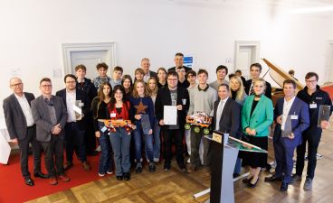 Eine Gruppe Schüler*innen aus Neumarkt posiert mit mehreren Erwachsenen für ein Foto bei der Preisverleihung.