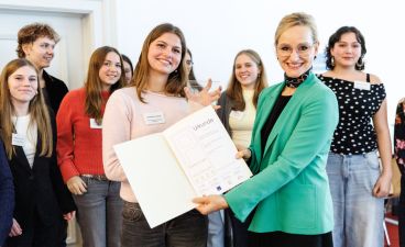Sandra Stenger, bbw-Vorstandsvorsitzende, überreicht den Schüler*innen des Albert-Einstein-Gymnasiums in München die Urkunde zum P-Seminar-Preis.