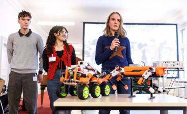 Drei Schüler*innen präsentieren ihren selbstgebauten Roboter.