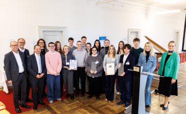 Eine Gruppe Schüler*innen aus dem Allgäu posiert mit mehreren Erwachsenen für ein Foto bei der Preisverleihung.