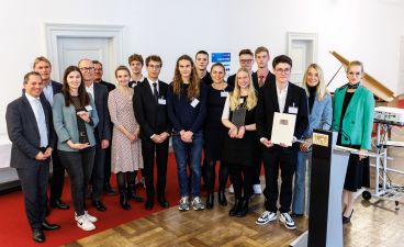 Eine Gruppe Schüler*innen aus Augsburg posiert mit mehreren Erwachsenen für ein Foto bei der Preisverleihung.