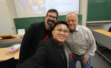 Drei Männer posieren für ein Selfie, um die Abschlussarbeit des Mannes in der Mitte zu feiern.