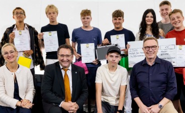 Die Gewinner des dritten Platzes: Eine Gruppe von Schülern posiert mit Wilfried Hüntelmann (links, Geschäftsführer Agentur für Arbeit München), Sandra Stenger (bbw-Vorstandsvorsitzende) und Tobias Gotthardt (Staatssekretär Bayerisches Wirtschaftsministerium).