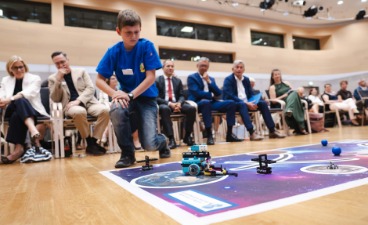 Selbstentwickelter Roboter Ein Junge führt dem Publikum auf einer markierten Fläche am Boden den selbstentwickelten Roboter vor.