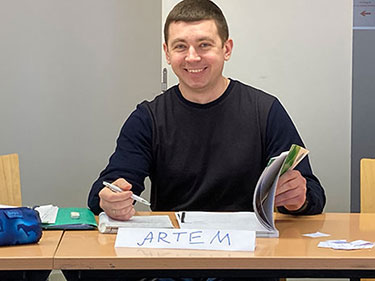Ein Mann sitzt an einem Schreibtisch und schreibt in einem Arbeitsheft.