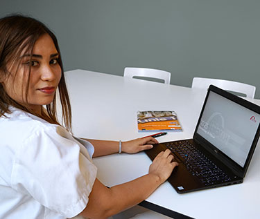 Eine junge Frau sitzt vor ihrem Laptop und absolviert Online-Unterricht. 