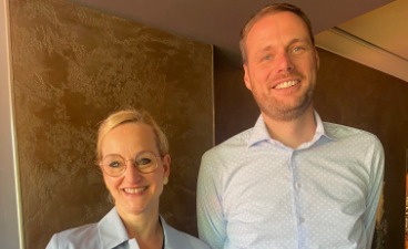 Eine Frau und ein Mann stehen nebeneinander und lachen in die kamera.