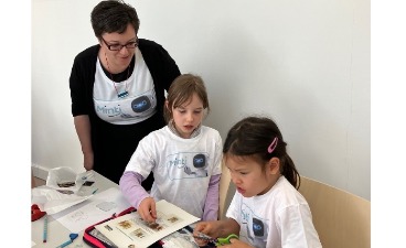 Nach der Theorie folgt die Praxis: Eva Hinterhuber, Projektleiterin im Bildungswerk der Bayerischen Wirtschaft e. V. bastelt mit Grundschülerinnen an ihrem MINT-Projekt (Copyright: Doreen Dambacher)