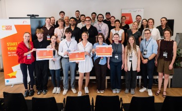 Gruppenfoto der teilnehmenden Studierenden, Jurymitglieder sowie Organisatorinnen und Organisatoren des 5-Euro-Business Wettbewerbs mit Urkunden bei der Abschlussveranstaltung an der Hochschule Ansbach.