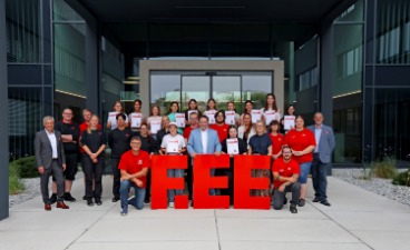 Gruppenbild der Teilnehmerinnen des Mädchen für Technik-Camps mit Ehrengästen und Betreuenden vor großen roten F.EE-Buchstaben.